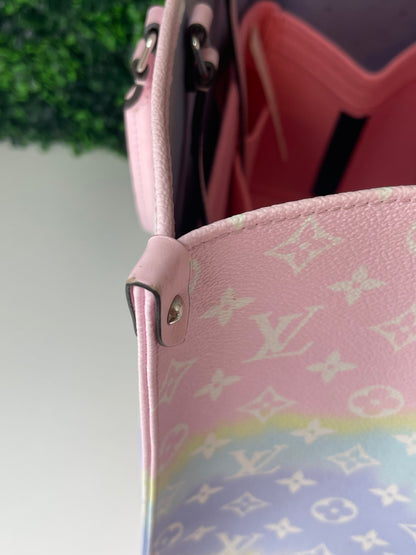 Top corner view of a pink and multicolor patterned Louis Vuitton OnTheGo Escale handbag GM with a structured handle and straps.