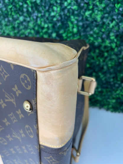 Bottom corner of a preowned Louis Vuitton Monogram Beverly GM handbag with a brown and beige color scheme, tan leather trim, featuring the brand's iconic LV logo.
