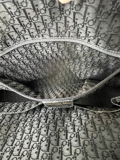 Interior view with dark cloth and Dior label on the interior with a slip pocket and zipper pocket of a Preowned Dior black leather handbag.