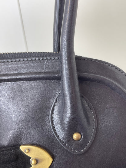 Zoomed in photo of leather chaps and handle of Preowned Dior black leather handbag.