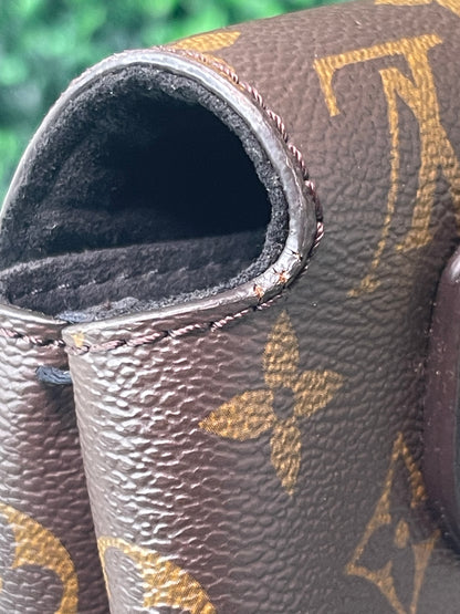 Zoomed in image of right side opening of A preowned Louis Vuitton Marignan handbag with brown and tan monogram. Shows some cracks in canvas.