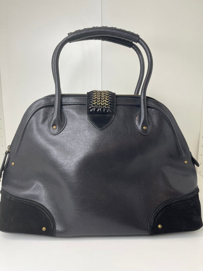 Back side view of a preowned Dior black leather handbag with black suede trim and aged brass hardware, featuring a braided top handle.