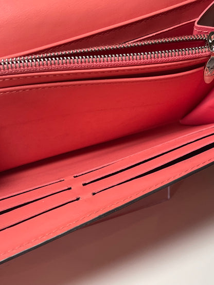 Top view of interior coin pouch and zipper with silver hardware and multiple card slots of a pink glossy preowned Louis Vuitton long wallet with vernis leather.