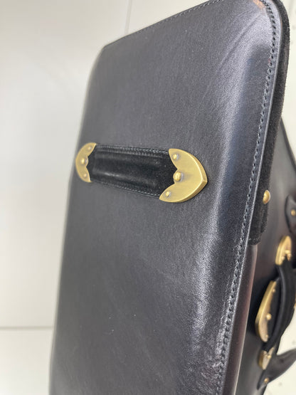 Bottom view of a preowned Dior black leather handbag with black suede trim and aged brass hardware.