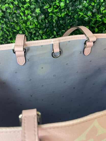 Zoomed in image of topwith blue cloth interior view of a pink base and multicolor patterned Louis Vuitton OnTheGo Escale handbag GM.