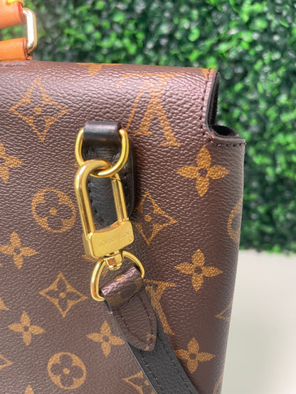 A preowned Louis Vuitton Marignan handbag in black color with a brown handle and a gold-tone hardware. Showing zoomed in image of back side of handbag. 