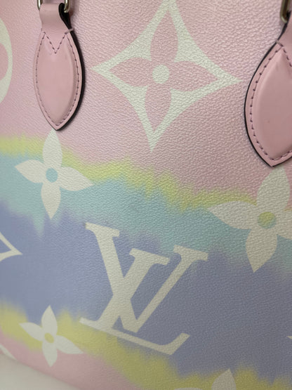 Zoomed in image of a pink and multicolor patterned Louis Vuitton OnTheGo Escale handbag GM with a structured handle and straps.