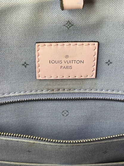 Louis Vuitton leather heatstamp on interior back with purple-blue cloth interior and zipper pocket with silver hardware of the Louis Vuitton OnTheGo Escale handbag GM. Shows some staining on interior. 