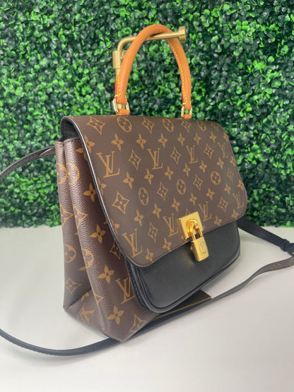 A preowned Louis Vuitton Marignan handbag in black color with a brown handle and a gold-tone hardware. View of left side of handbag. 