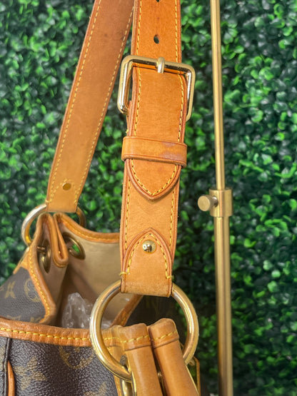 Side view of tan leather shoulder strap on a brown monogram Preowned Louis Vuitton Galliera PM with gold hardware.