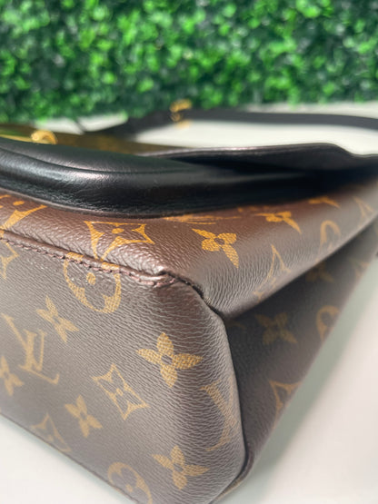 Bottom corner of brown and tan monogram canvas of a a preowned Louis Vuitton Marignan handbag. 