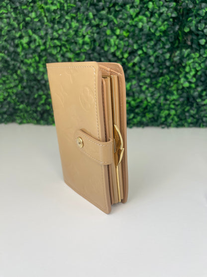 Side view of a preowned Louis Vuitton tan vernis leather wallet with a monogram pattern and a tan leather interior, featuring a lock and key mechanism.