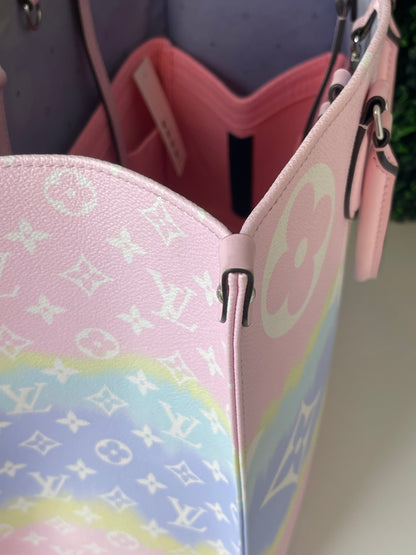 Top corner view of a pink and multicolor patterned Louis Vuitton OnTheGo Escale handbag GM with a structured handle and straps.