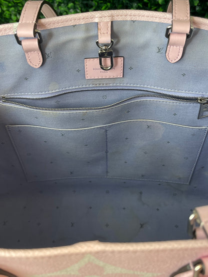 Top interior with purple-blue cloth interior of patterned Louis Vuitton OnTheGo Escale handbag GM. Shows some staining on interior. Zipper pocket with silver hardware.