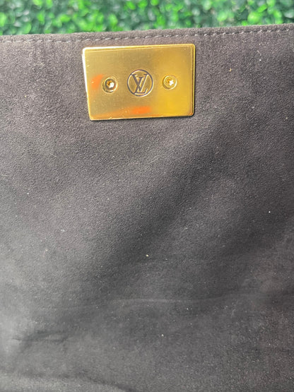 Black cloth interior with gold hardware inside of a preowned Louis Vuitton Marignan handbag. 