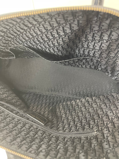 Interior view with dark cloth interior and Dior monogram inside of a preowned Dior black leather handbag. 