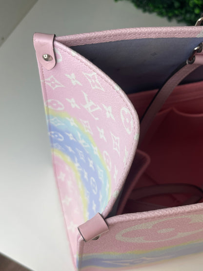 Zoomed in image of top corner view of a pink base and multicolor patterned Louis Vuitton OnTheGo Escale handbag GM.