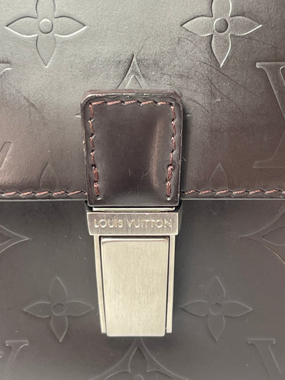 Metal clasp on front view of brown handbag 