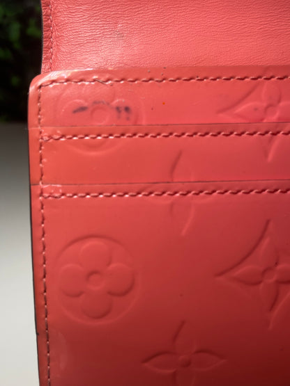 Interior corner with some color transfer on a pink glossy preowned Louis Vuitton long wallet with vernis leather.