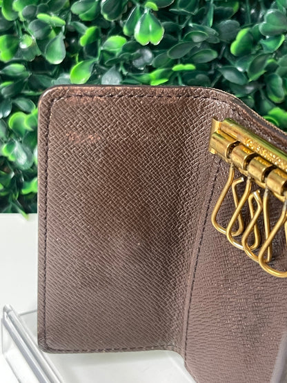 Interior left side view of Front view of a preowned Louis Vuitton Damier Ebene Multicles 4 Key Holder with brown damier canvas on exterior and gold-tone hardware.