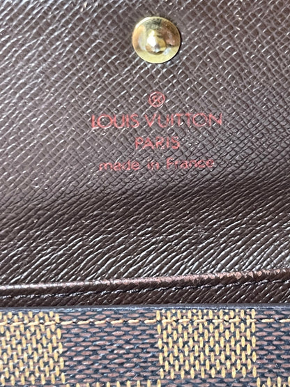 Louis Vuitton heat stamp in red lettering on brown interior canvas of a preowned Louis Vuitton Damier Ebene Multicles 4 Key Holder.