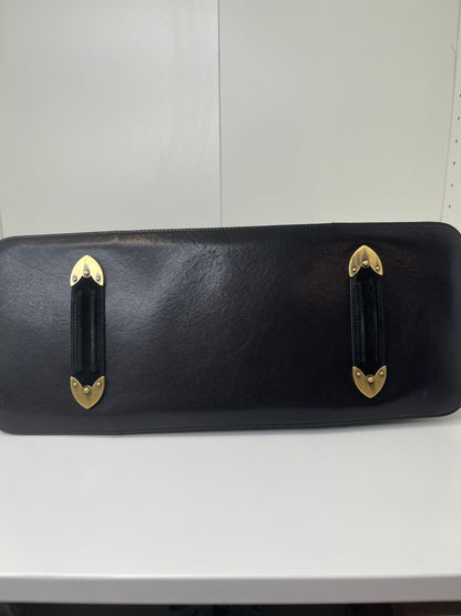 Bottom view with a preowned Dior black leather handbag with black suede trim and aged brass hardware.