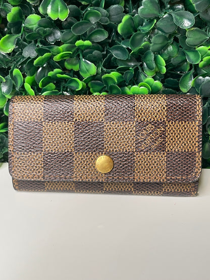 Front view of a preowned Louis Vuitton Damier Ebene Multicles 4 Key Holder with brown damier canvas and gold-tone hardware.
