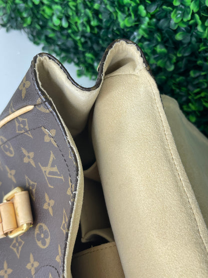 Interior top corner of a preowned Louis Vuitton Monogram Beverly GM handbag with a brown and beige color scheme, tan leather trim, featuring the brand's iconic LV logo and gold hardware.