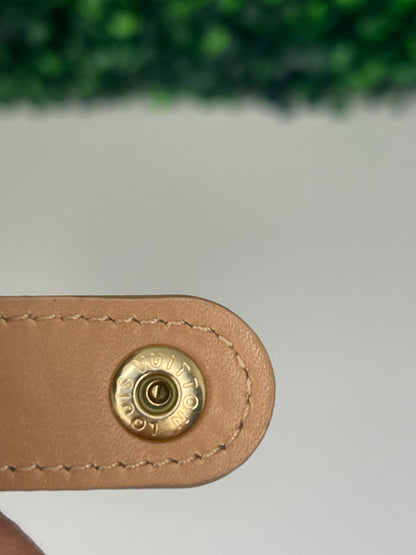 Button clasp hardware of a preowned Louis Vuitton tan vernis leather wallet with a monogram pattern and a tan leather interior.