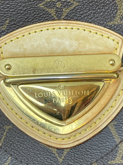Zoomed in photo of metal clasp on front of handbag with tan leather trim on A preowned Louis Vuitton Monogram Beverly GM handbag with a brown and beige color scheme, featuring the brand's iconic LV logo.