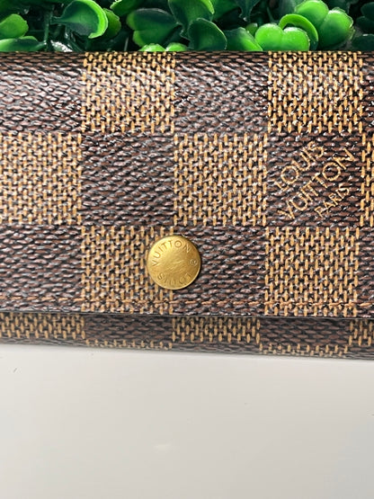 Zoomed in front view of a preowned Louis Vuitton Damier Ebene Multicles 4 Key Holder with brown damier canvas and gold-tone hardware.
