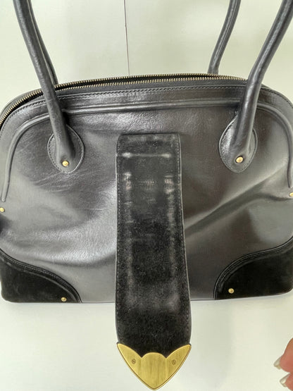 Back side view with suede clasp open of preowned Dior black leather handbag with black suede trim and aged brass hardware, featuring a braided top handle. Shows some wear and rubs on interior clasp.