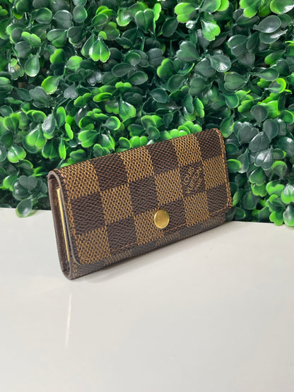 Side view of a preowned Louis Vuitton Damier Ebene Multicles 4 Key Holder with brown damier canvas and gold-tone hardware.