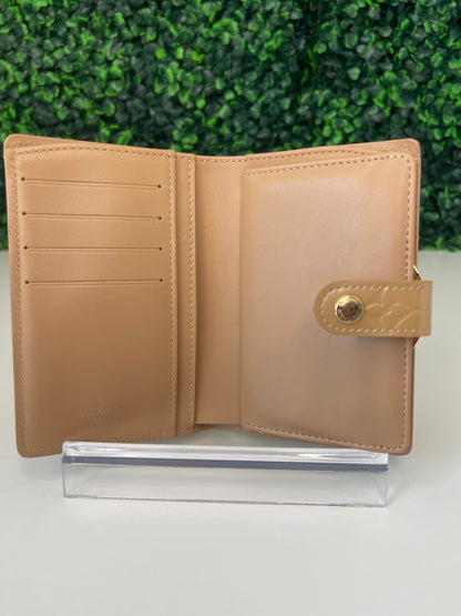Interior view of a preowned Louis Vuitton tan vernis leather wallet with a monogram pattern and a tan leather interior, featuring a lock and key mechanism and card slots.